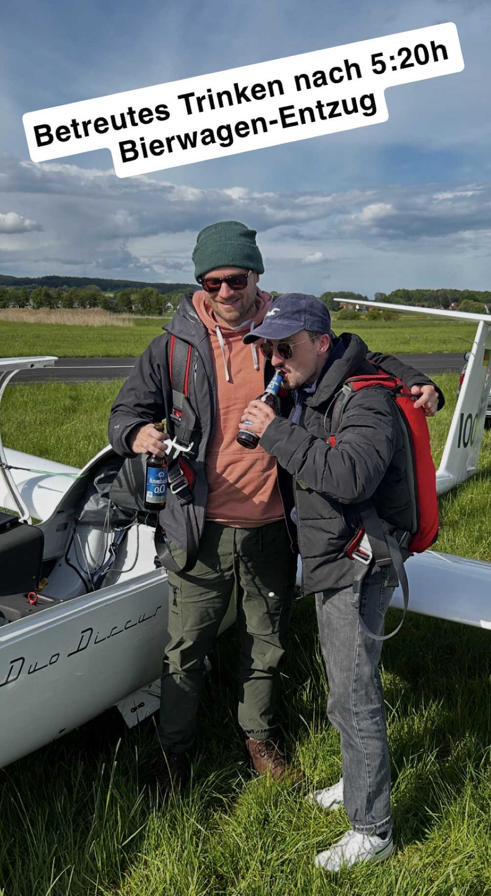Zwei Piloten lachen neben einem Segelflugzeug